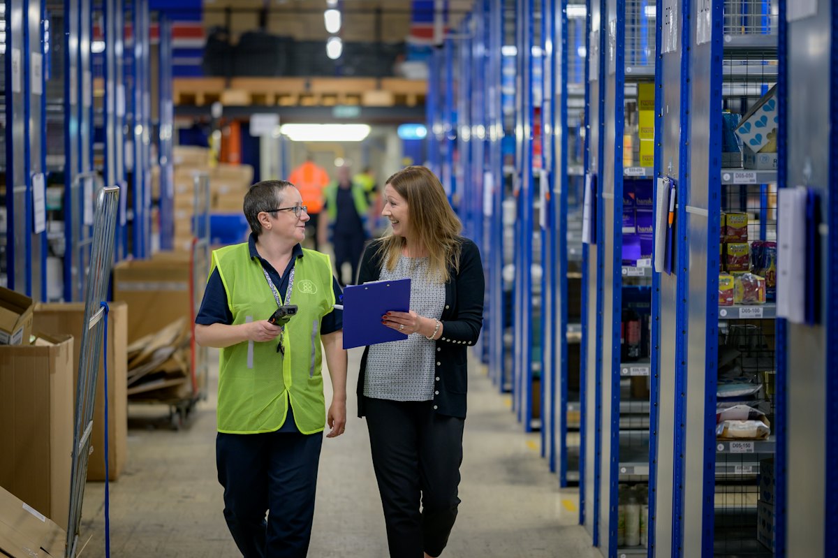 Two workers walking down a logistics warehouse aisle