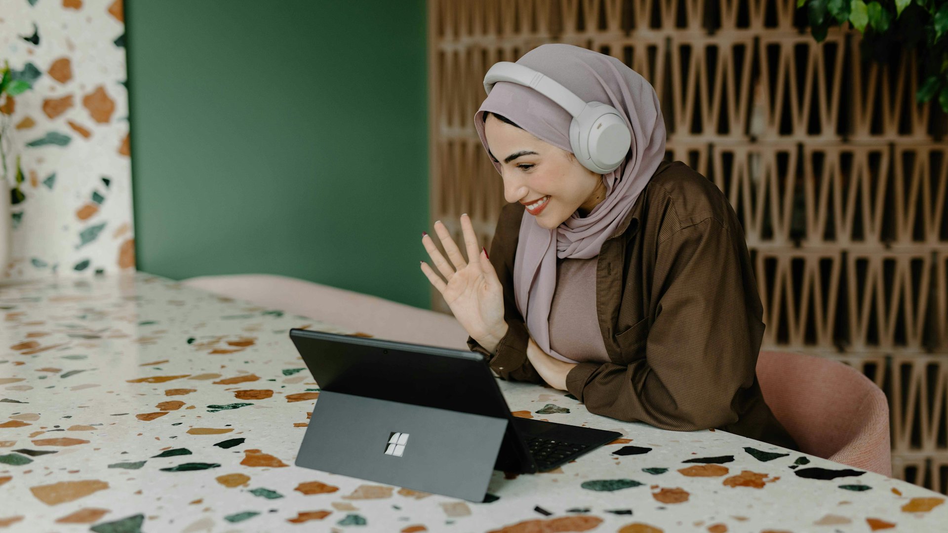 Perempuan berhijab melakukan panggilan video lewat laptop di rumah