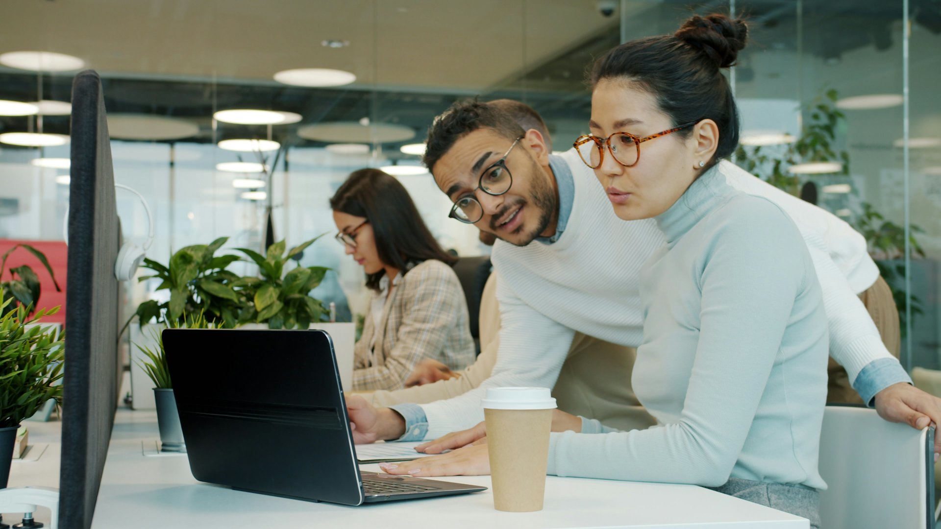 Dua rekan kerja berdiskusi di depan laptop di kantor