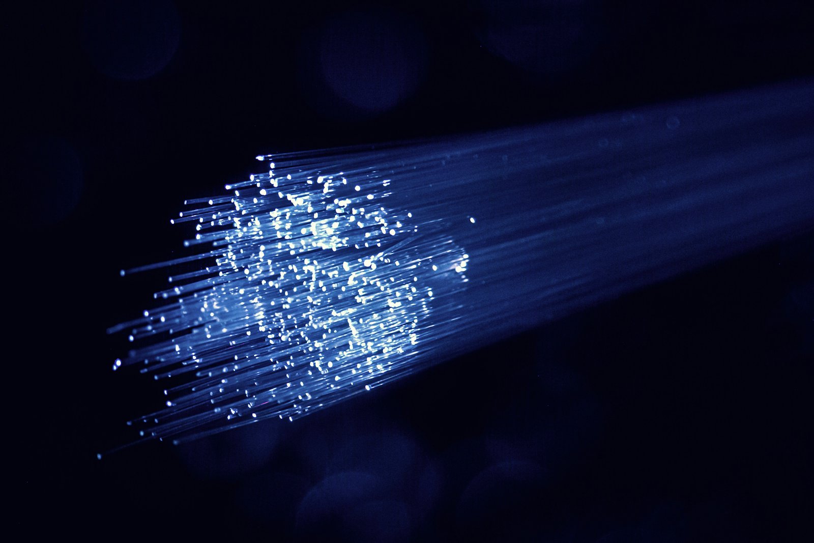 Ujung serat kabel fiber optik memancarkan cahaya biru